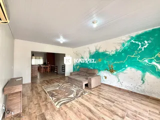 Sala de estar com sofá e parede decorada com um mural de rio turquesa.