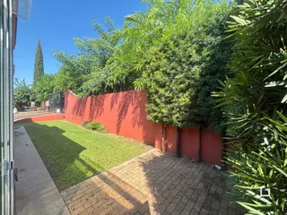 Vista do quintal com gramado e muro vermelho.