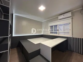 Ambiente interno moderno com piso de madeira e móveis em tons de cinza.