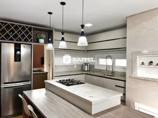Cozinha moderna com ilha central e armários em tons neutros.