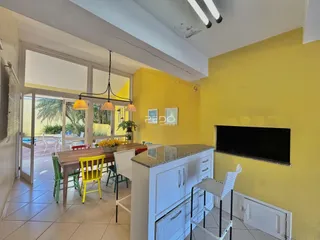 Ambiente interno de sala de jantar com cozinha e acesso ao exterior.