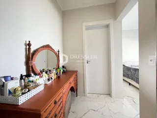 Quarto com cômoda e espelho em um ambiente claro.