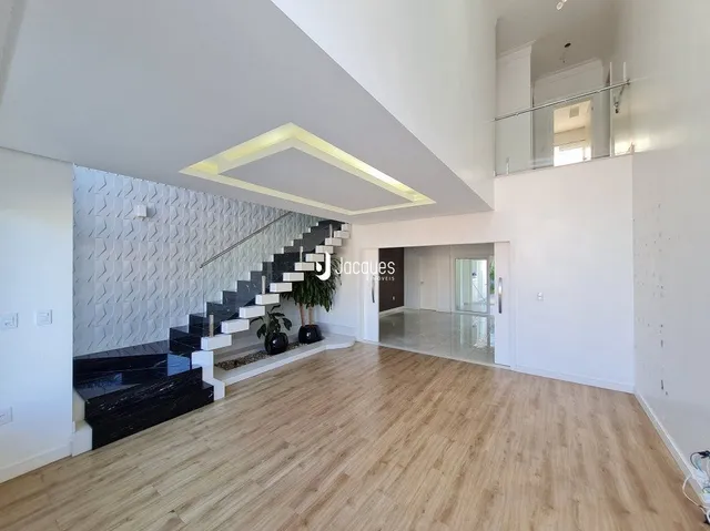 Sala de estar com piso de madeira e escadaria moderna.