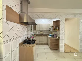 Vista da cozinha com armários e revestimento de azulejos brancos.