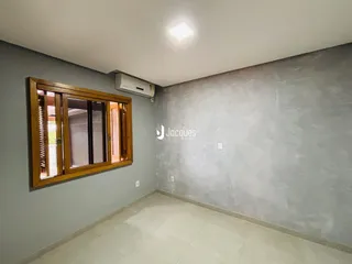 Interior de uma sala com parede cinza e piso claro.