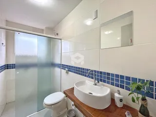 Foto de um banheiro com azulejos azuis e box de vidro.