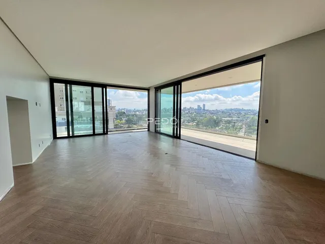 Sala de estar ampla com piso de madeira e vista da paisagem urbana.