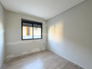Ambiente interno de uma sala com piso de madeira e janela.