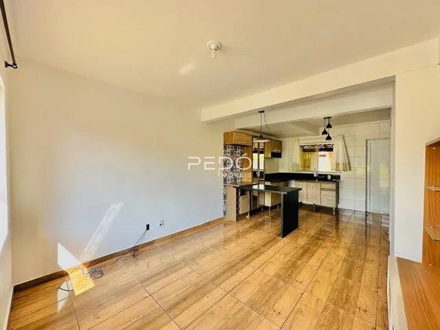 Sala de estar ampla com piso de madeira clara e paredes brancas.
