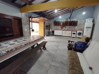 Sala com piso de madeira e banco longo na área interna da residência.