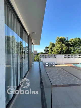 Vista da fachada de um imóvel com grandes janelas de vidro e área externa.