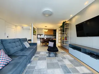 Sala de estar moderna com sofá e televisão em um apartamento no Brasil.