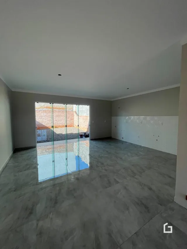 Interior de uma sala ampla com piso de concreto e porta de vidro.