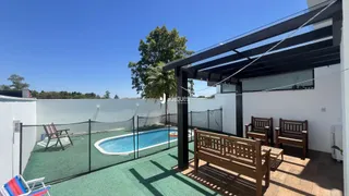Vista da piscina e área externa com pergolado de madeira de uma residência.