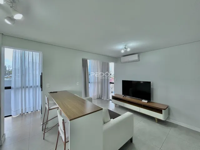 Sala de estar com sofá e mesa de madeira em um apartamento.