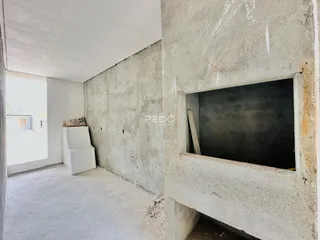Interior de um espaço com paredes de concreto aparente em construção.