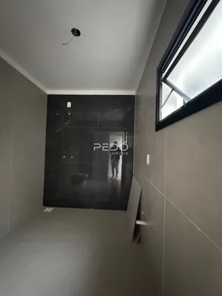Vista de um corredor interno com parede escura e janela no ambiente.