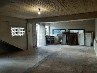 Foto de um ambiente interno com teto de vigas exposto e paredes brancas.