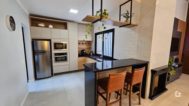 Interior de uma cozinha moderna com armários e ilha em Lajeado.
