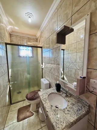 Banheiro com revestimento cerâmico e box de vidro.