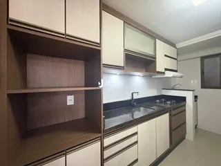 Vista da cozinha com armários planejados e bancada escura.
