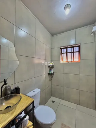 Foto interna de um banheiro com revestimento de azulejos claros.