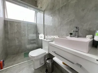 Banheiro moderno com pia branca e vaso sanitário em um imóvel.