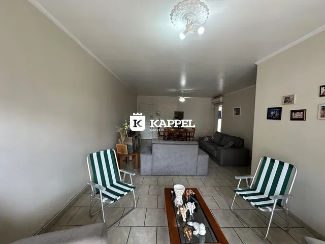 Uma sala de estar com sofá e cadeiras listradas é visível no interior da residência.