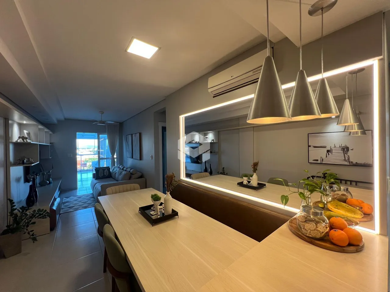 Sala de estar e cozinha moderna com iluminação suspensa.