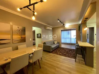 Sala de estar com piso de madeira e mesa de jantar.