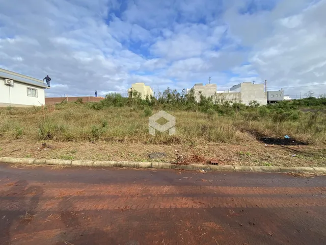 Vista externa de uma propriedade com vegetação densa e construções ao fundo.