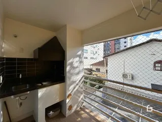 Vista interna de uma área com bancada escura e piso de madeira.