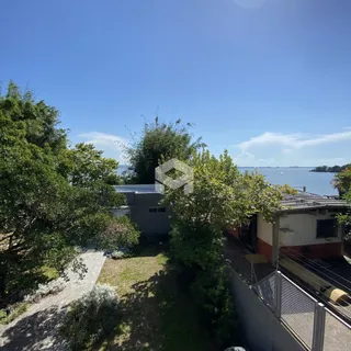 Vista externa da propriedade com vegetação e paisagem costeira.