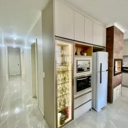 Hall de entrada com armários brancos e um refrigerador de vidro.