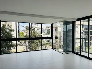 Sala de estar com grandes janelas que oferecem vista para a rua e árvores.