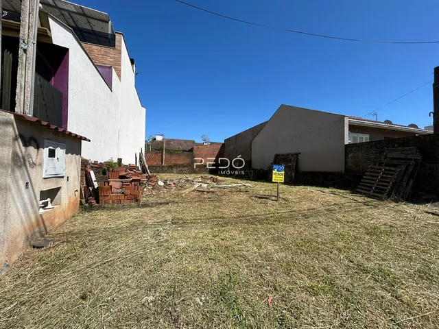 Vista externa de uma propriedade com terreno gramado e construções adjacentes.