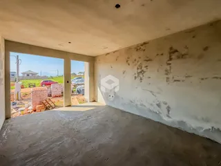 Interior de uma sala com paredes desgastadas e piso de concreto.
