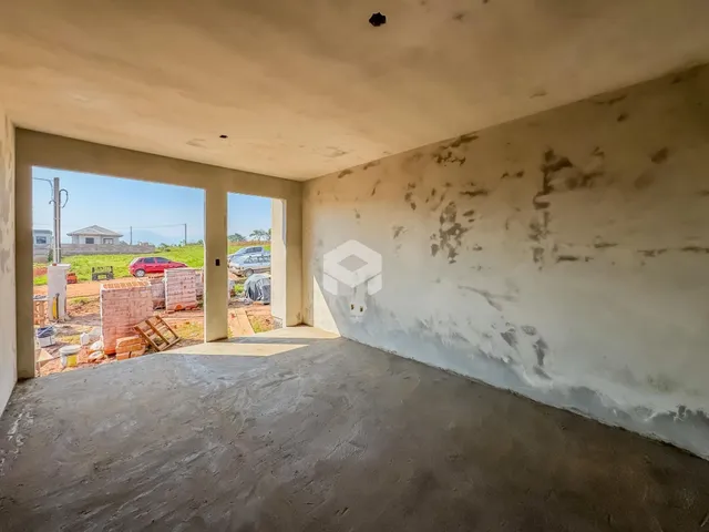 Interior de uma sala com paredes desgastadas e piso de concreto.