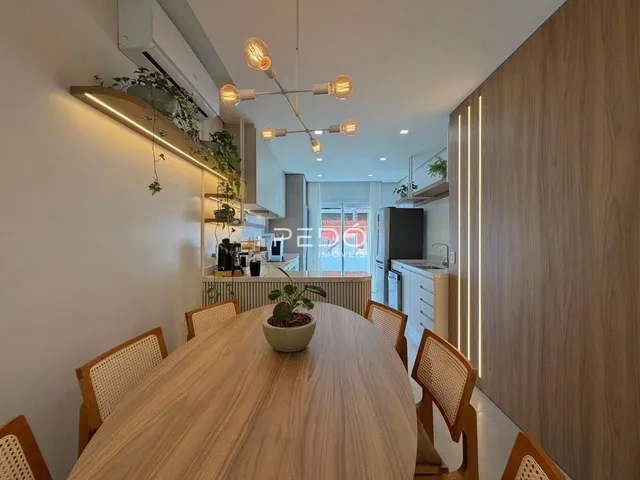 Uma sala de jantar com mesa de madeira e cadeiras em um apartamento.