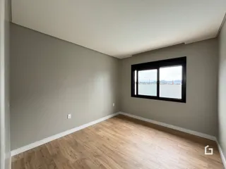 Ambiente interno de uma sala com piso de madeira e janela.