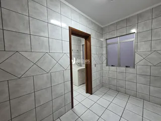 Hall de entrada com piso de cerâmica e paredes revestidas de azulejos brancos.