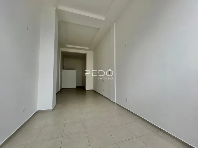Corredor interno de um imóvel com paredes brancas e piso claro.