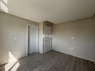 Ambiente interno de uma sala com piso de madeira e porta de entrada.