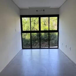 Ambiente interno com grande janela de vidro que oferece vista para a vegetação.
