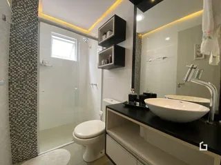 Foto de um banheiro moderno com box de vidro e louças brancas.