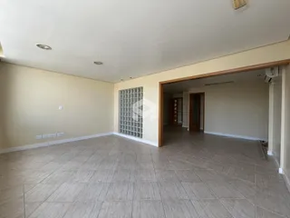 Interior de uma sala ampla com piso de cerâmica e parede com grade.