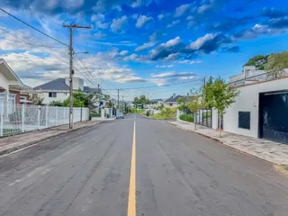 Vista de uma rua residencial em Lajeado, Brasil com casas e cerca.