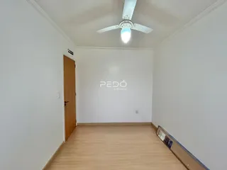 Ambiente interno de uma sala com piso de madeira clara e paredes brancas.
