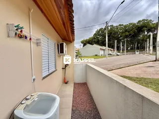 Foto da parede externa de uma residência mostrando venezianas brancas e um vaso sanitário.