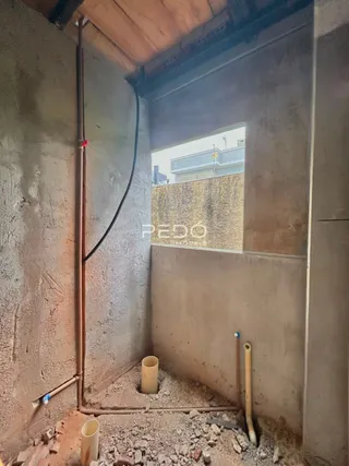 Parede interna com tubulações expostas em uma construção.